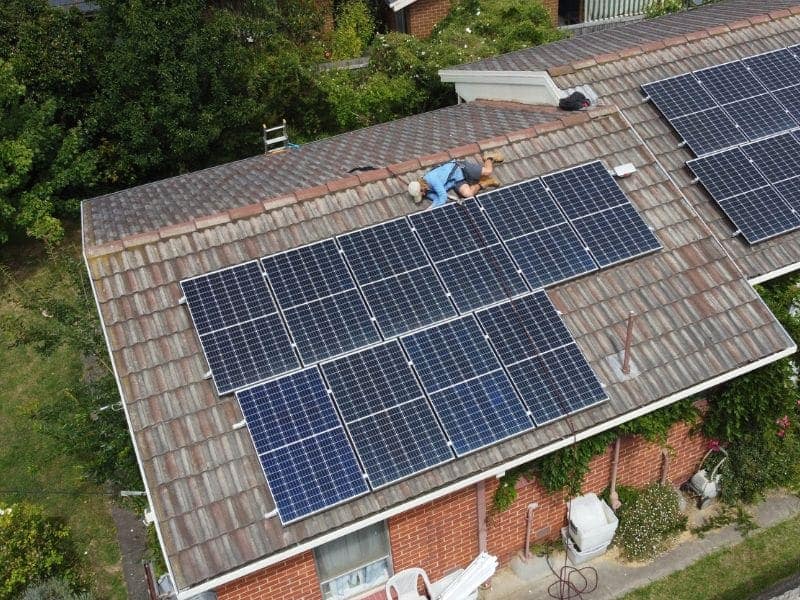 Tom on the roof inspecting underneath an old solar panel.